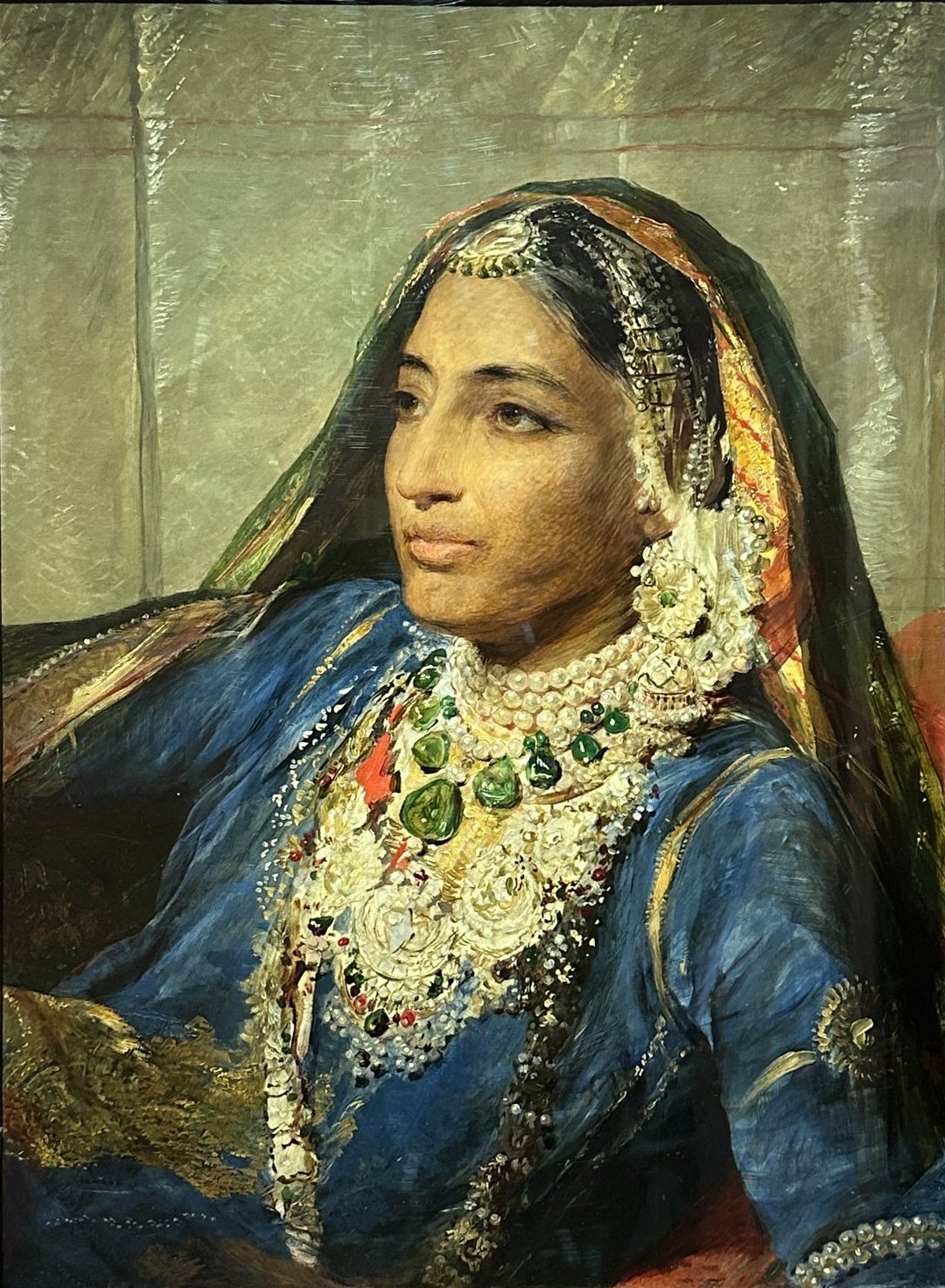 An oil portrait of a woman in a deep blue robe and a gold-bordered veil, wearing heavy necklaces of pearls and emeralds, her face turned to the left