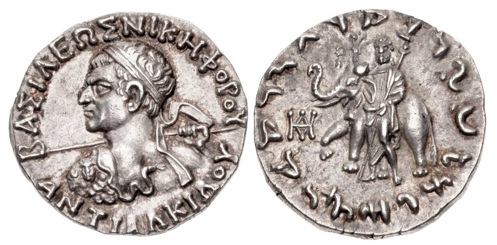 Both faces of a small silver coin: a king's head with a Greek inscription round it, and on the other side Zeus beside an elephant, with an inscription in Kharosthi letters