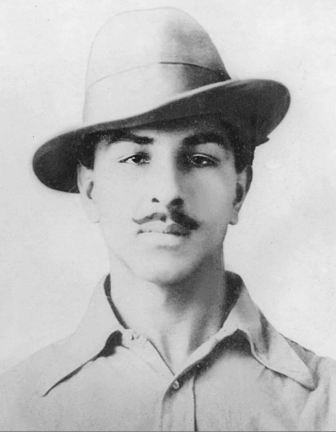 Head-and-shoulders portrait of Bhagat Singh as a young man, in a felt hat with a turned-down brim and an open-collared shirt, looking straight at the camera.