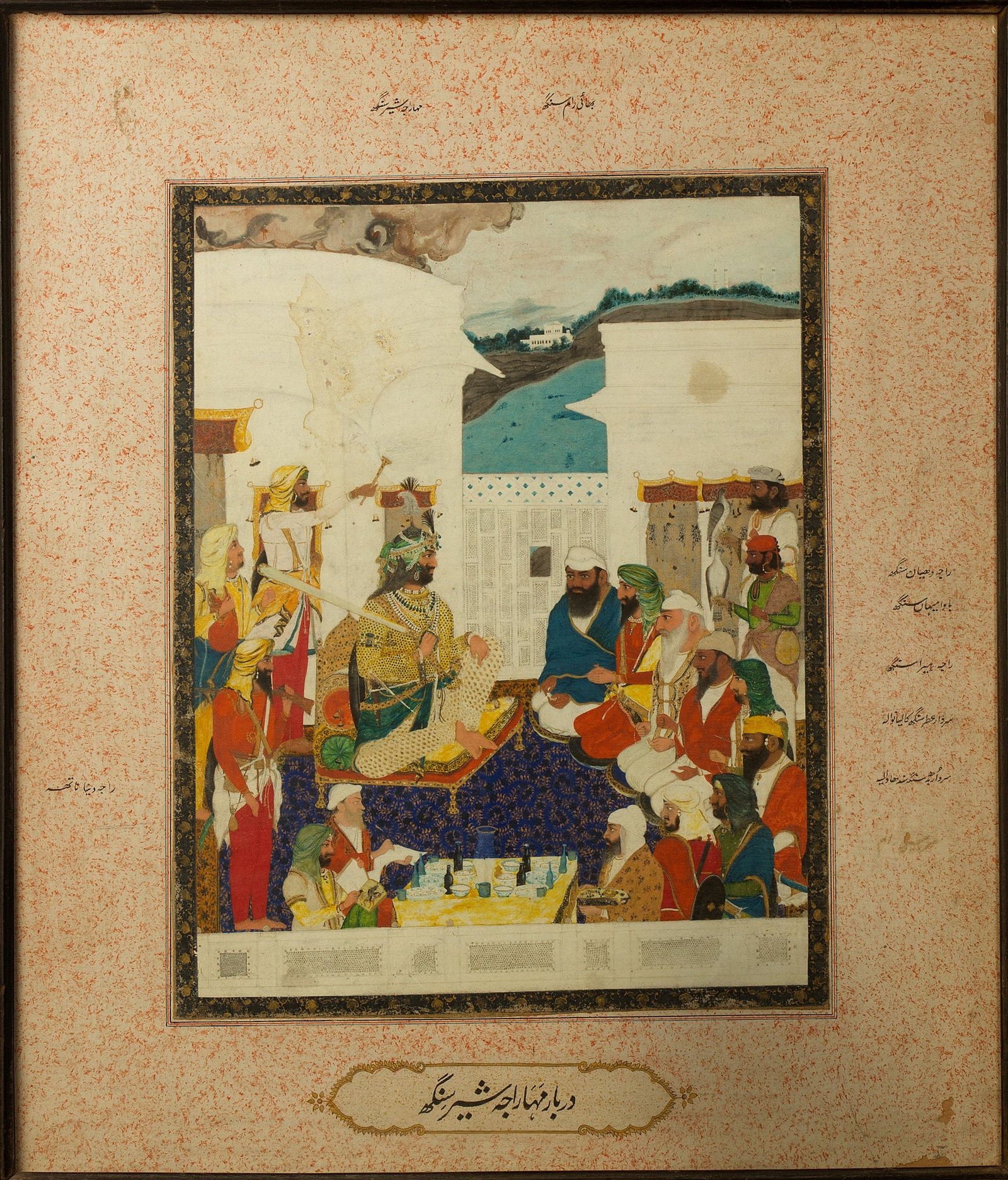 Painting of a Sikh court: the maharaja, crowned with a plumed turban ornament, sits on a cushioned throne under a pavilion's arches, with courtiers in coloured turbans around him and a river and far bank visible behind. Names are written in Persian script in the margins.