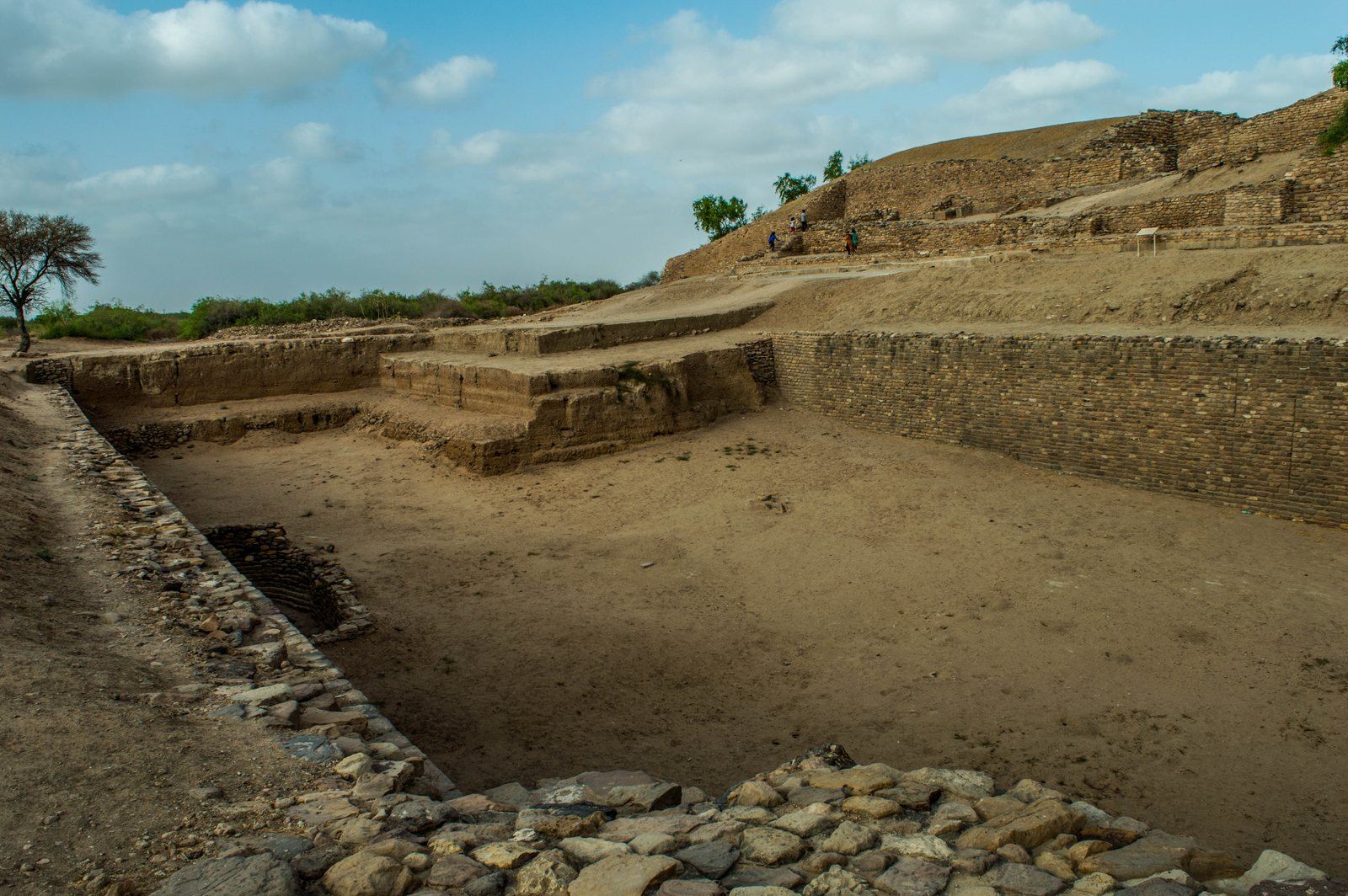 A deep rectangular reservoir at Dholavira with stone-lined sides and steps, under a blue sky
