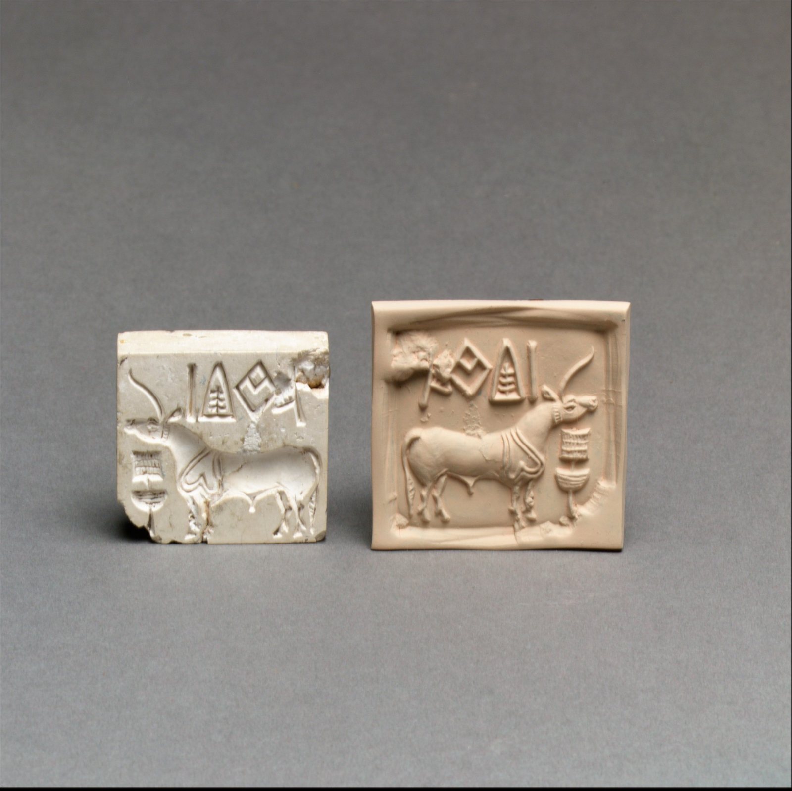 A square stone seal carved with a one-horned animal beneath a line of signs, beside its pale modern impression