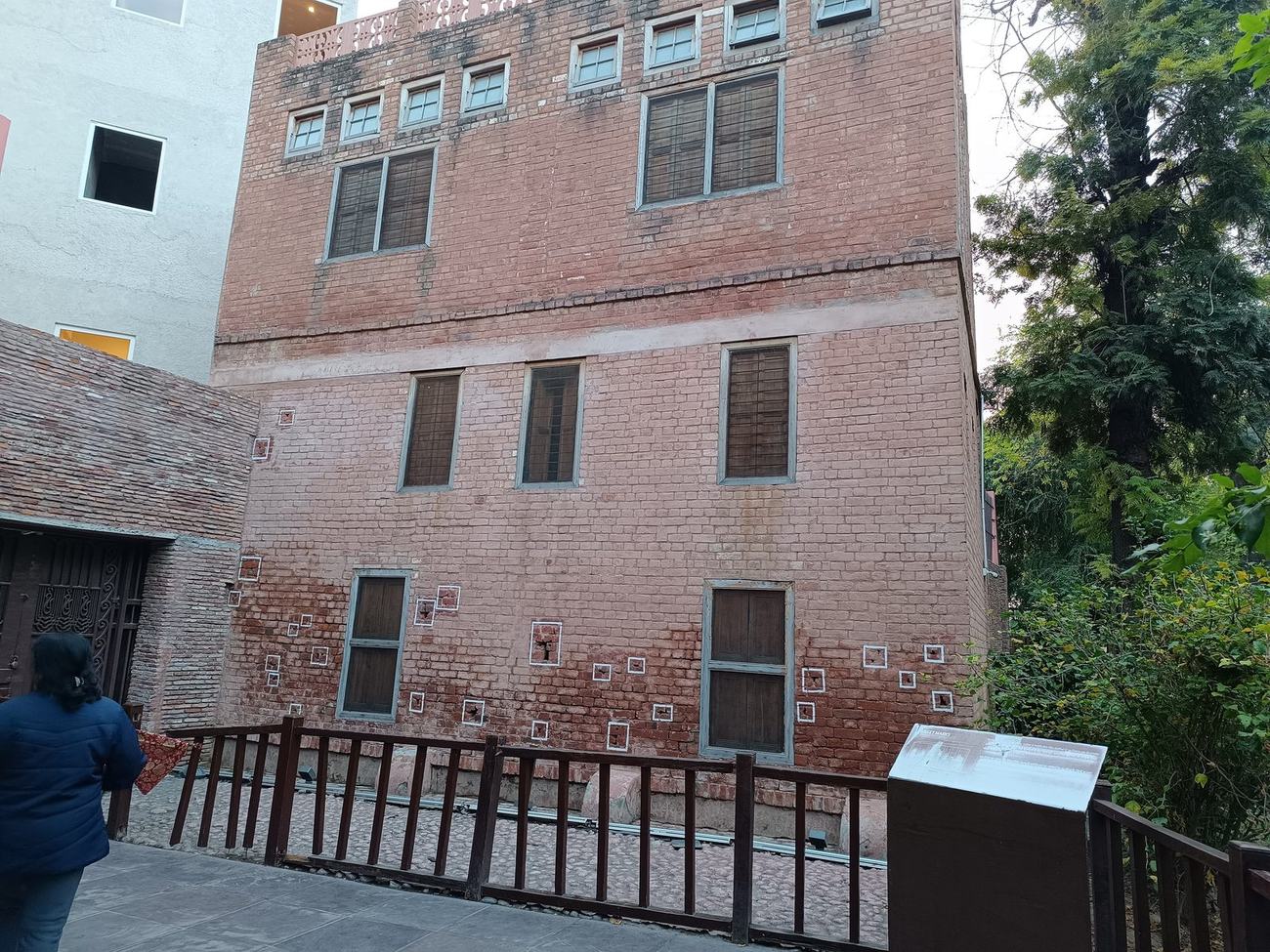 A preserved brick wall at the Jallianwala Bagh memorial with bullet strikes marked in white.