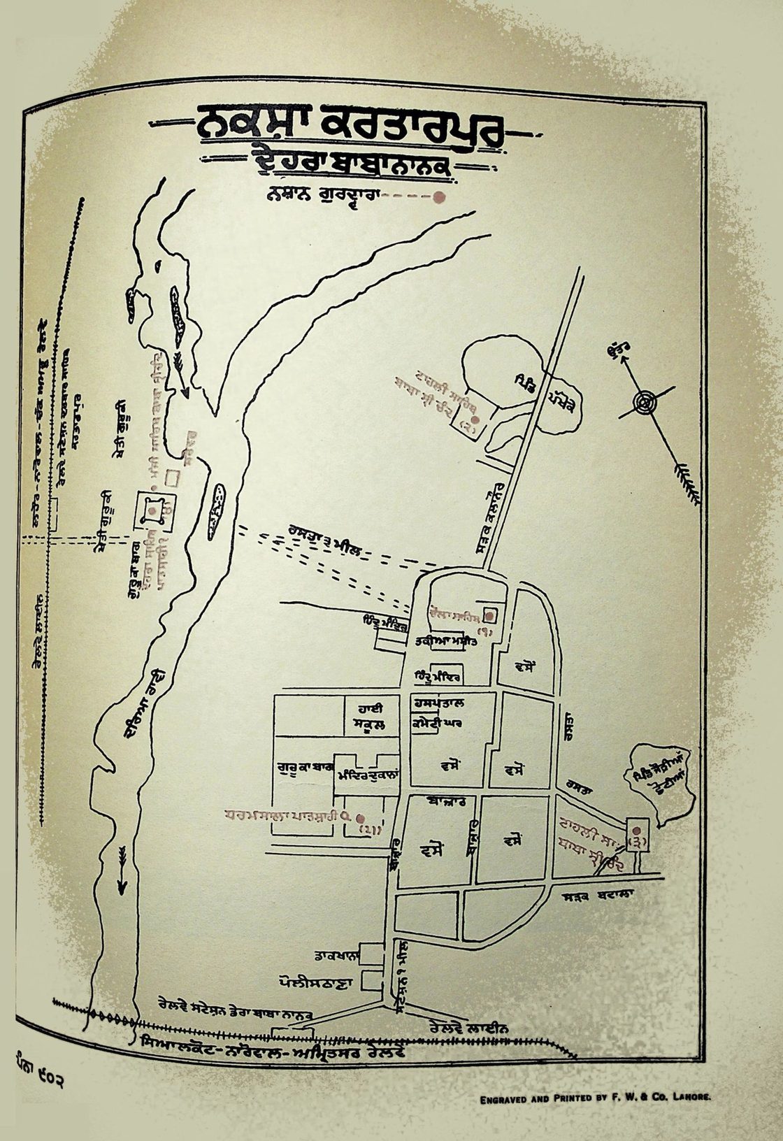 A printed map with Gurmukhi labels: a river runs down the left side, with a walled shrine and fields on its far bank, and on the near bank a village, a road and the grid of a small town, with a compass arrow at the top right