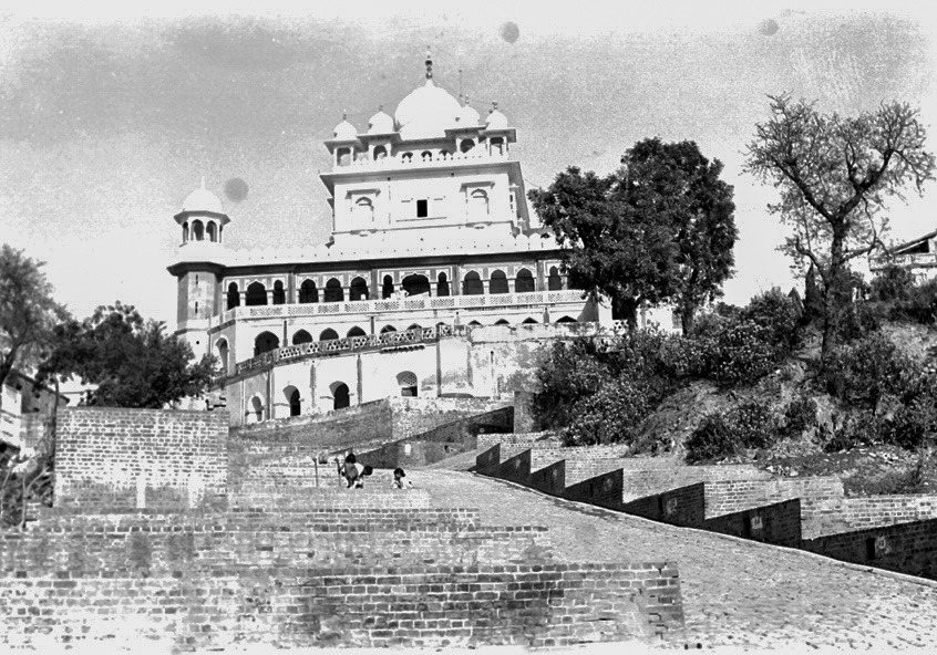 A black-and-white photograph of a white shrine with a fluted dome and small domed turrets on a hilltop, reached by a long brick ramp and flights of steps