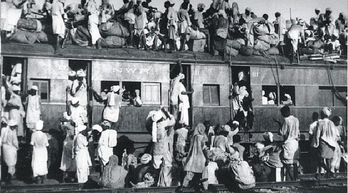 A train crowded far beyond capacity, refugees riding on the roof and clinging to the sides, during the Partition of 1947.