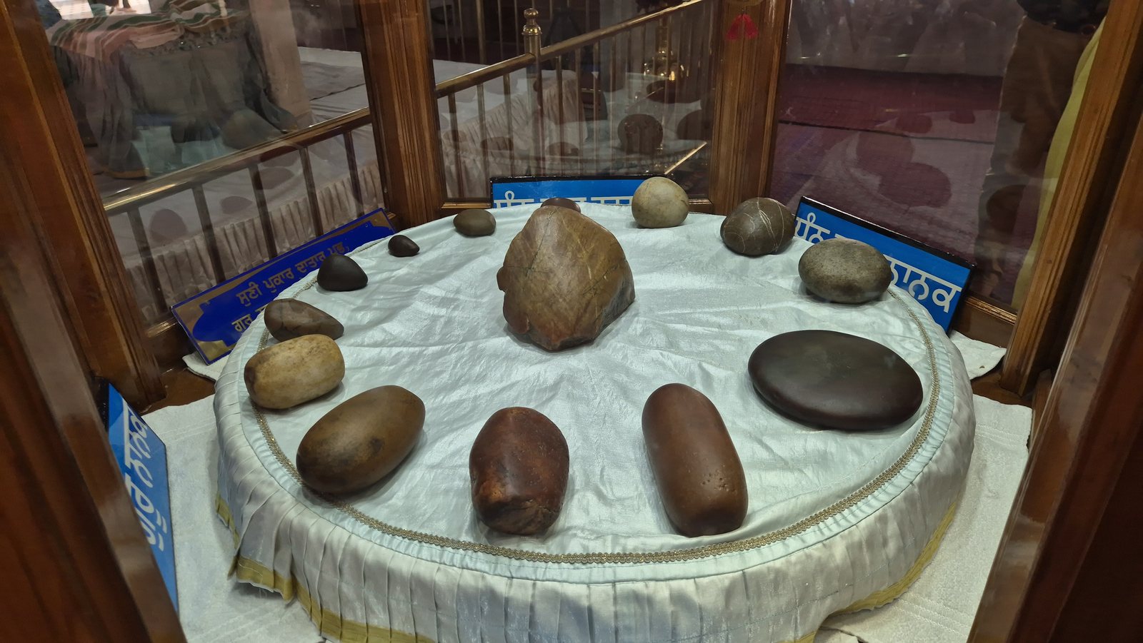 A round table under glass holding a dozen smooth stones of different sizes, oval and rounded, some dark, some reddish-brown