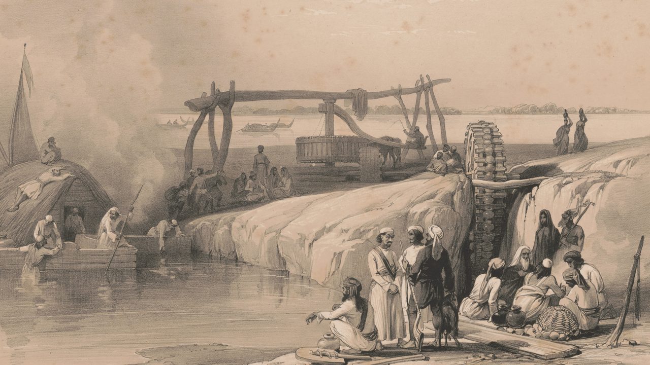 A tinted lithograph of a riverbank with boats, a wooden water-wheel and a lifting frame, and people gathered at the water's edge.
